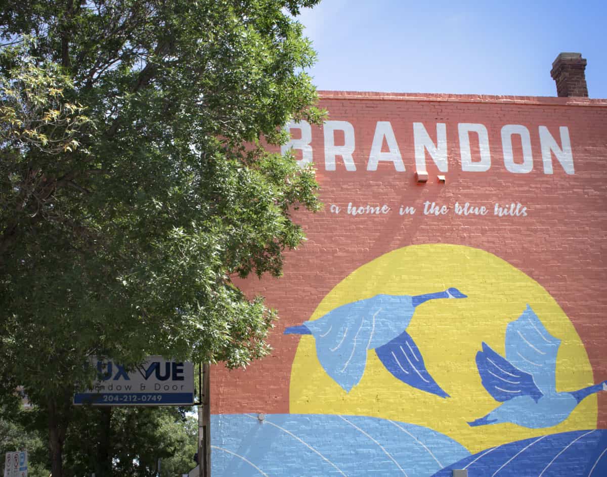 Colourful mural in Brandon, Manitoba with a tree framing it